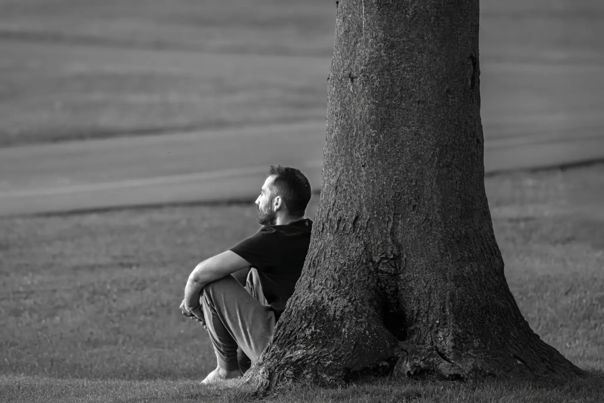 Man sitting alone by a tree in contemplation — grief counseling Los Angeles
