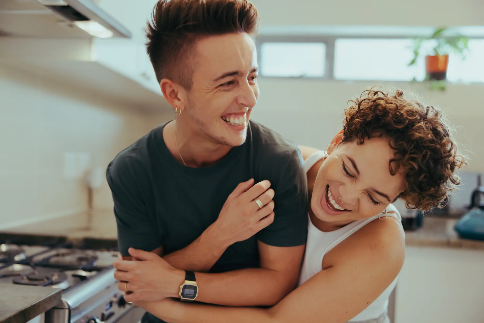 Couple laughing together in their kitchen, joyful and connected
